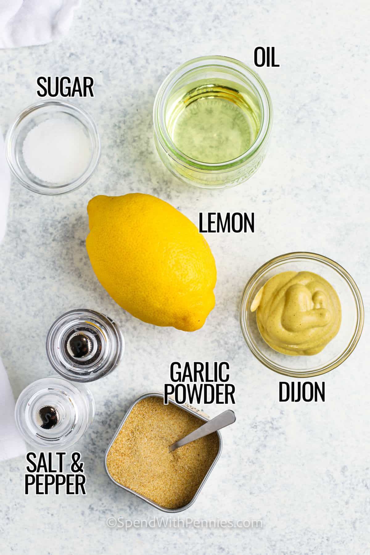 Suiker, olie, Dijon-citroen, knoflookpoeder, zout en peper met labels om een ​​gemakkelijke Dijon-saus te maken