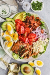 top view of Cobb Salad on a plate with ingredients and dressing around it