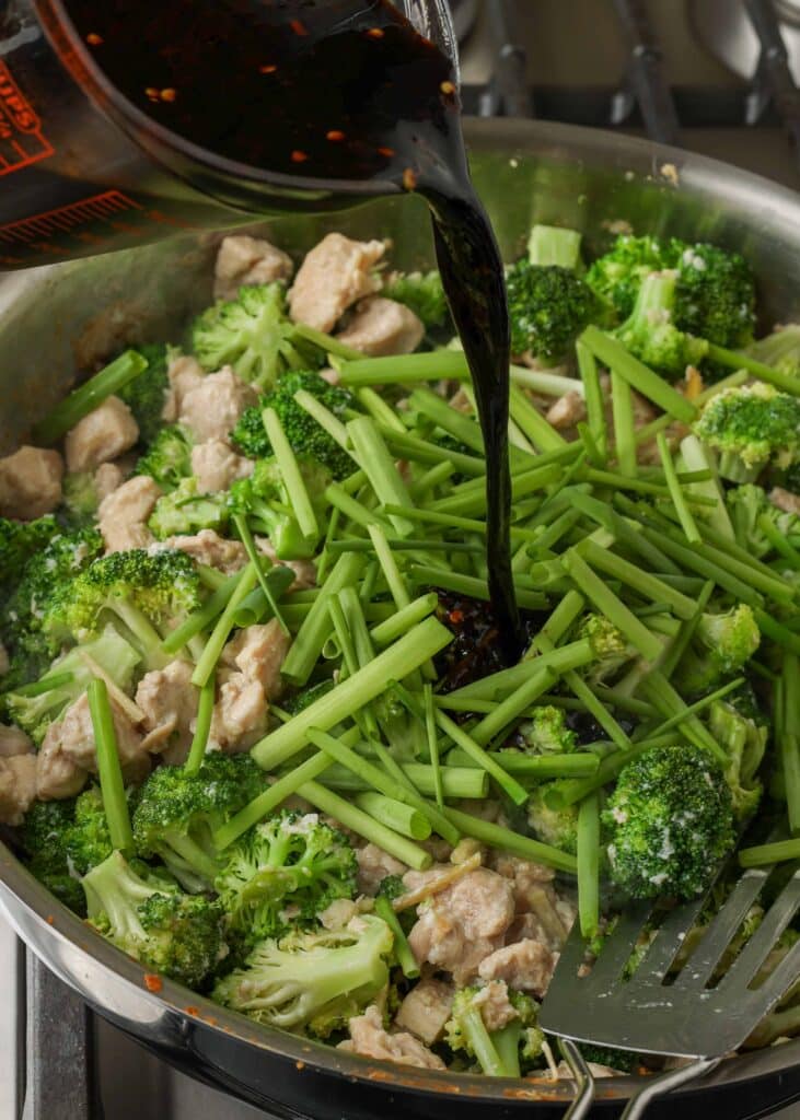 Schenk een scheutje van de roerbaksaus over de groenten in de koekenpan