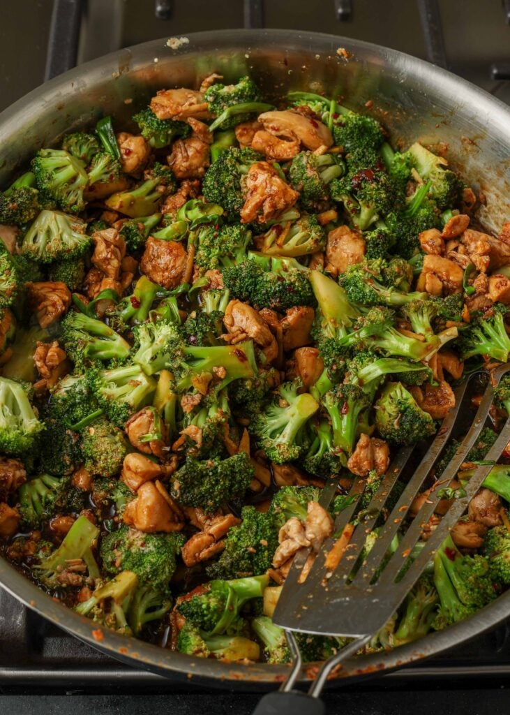 Gebakken kip met broccoli in een koekenpan met een lepel